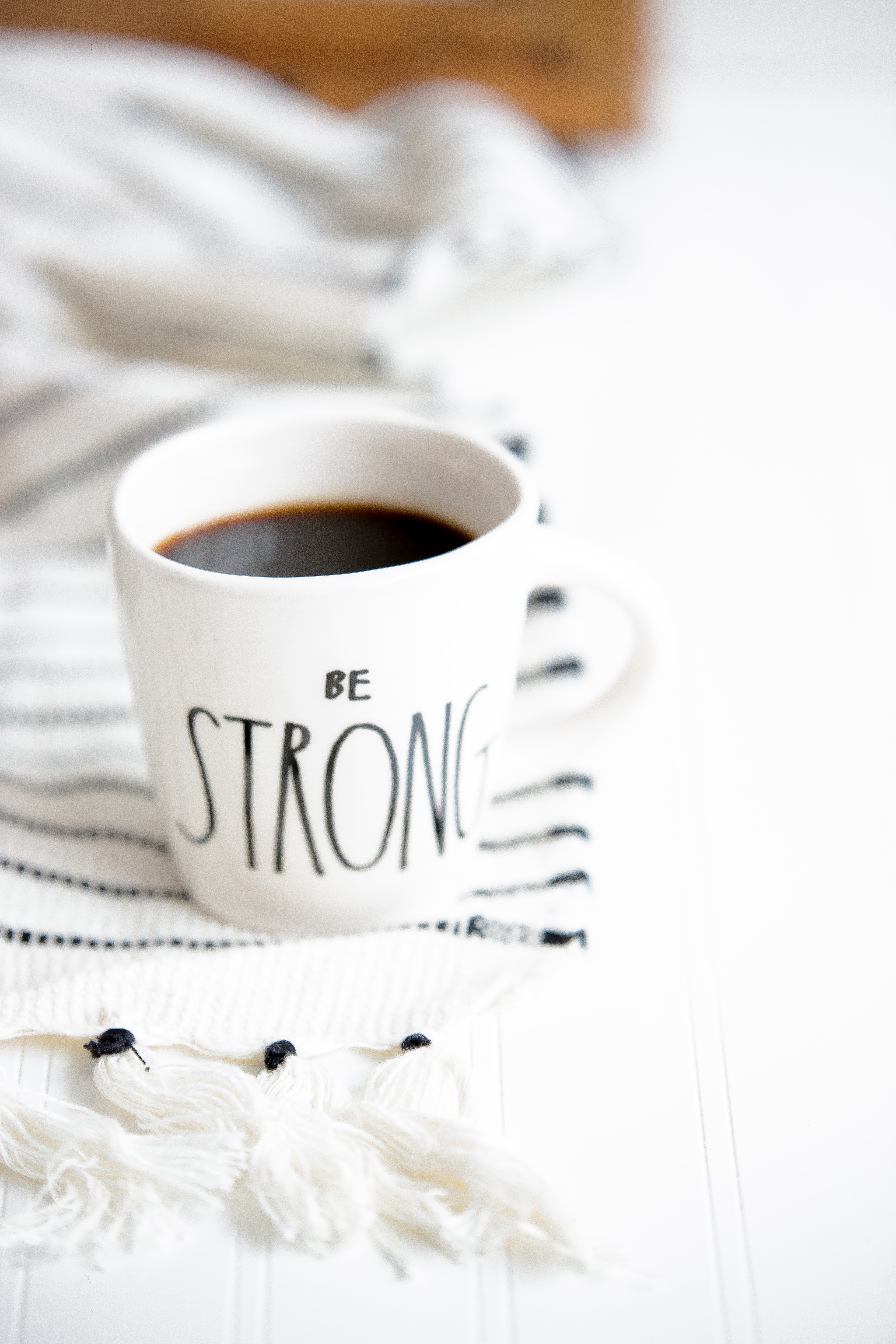 Motivational caption 'Be strong' on a mug